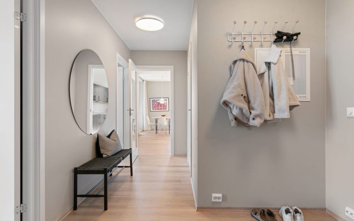 Small organized entryway with coats, shoes, a bench, and a clear walking path