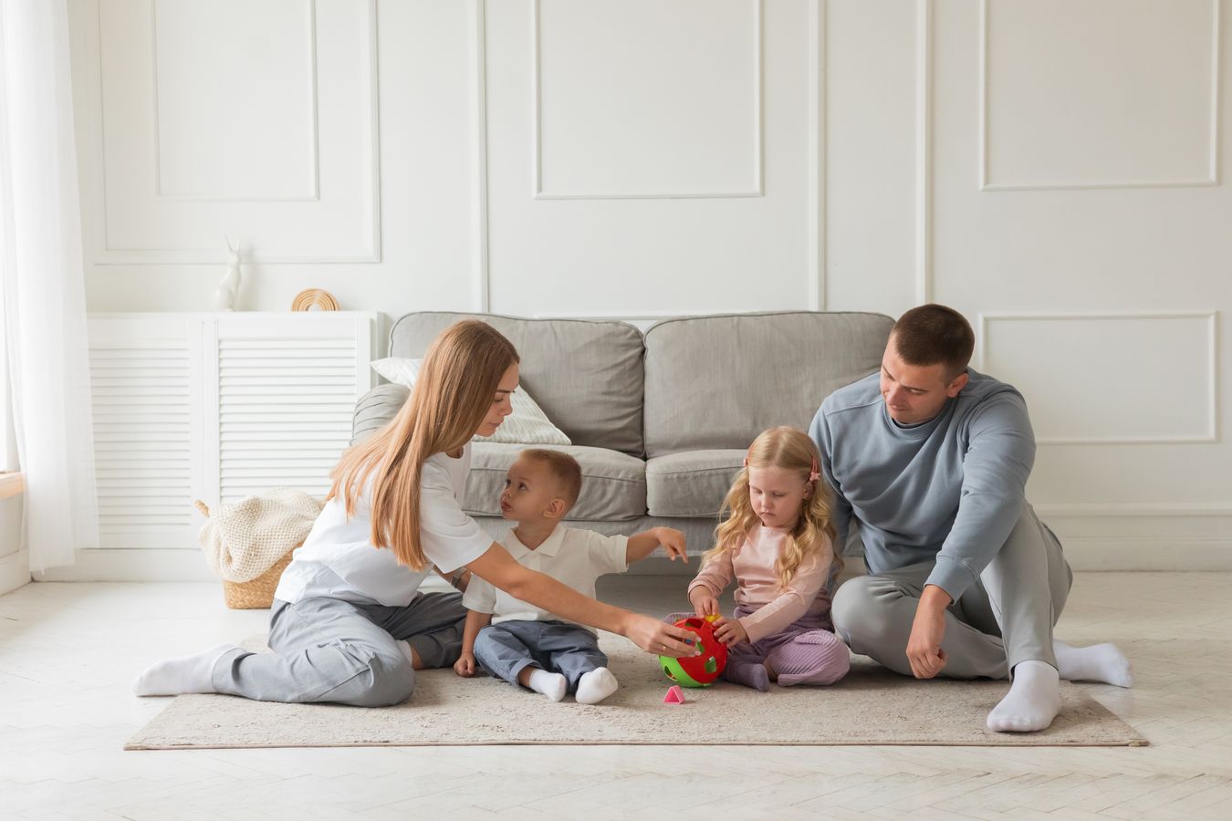 Family playing on the floor beside living-room seating, illustrating a child-friendly activity zone
