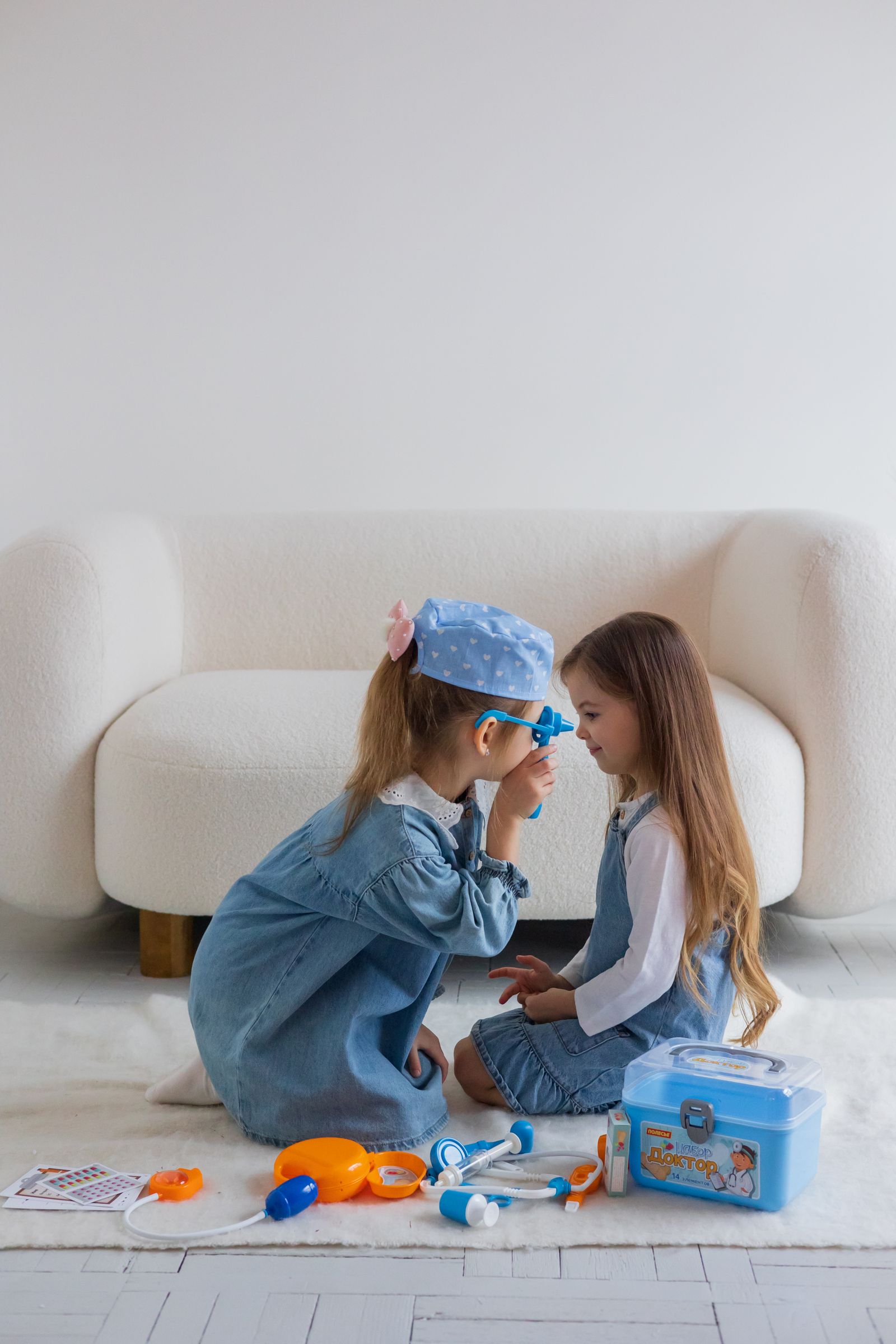 Two children playing with a pretend medical kit on a living-room rug