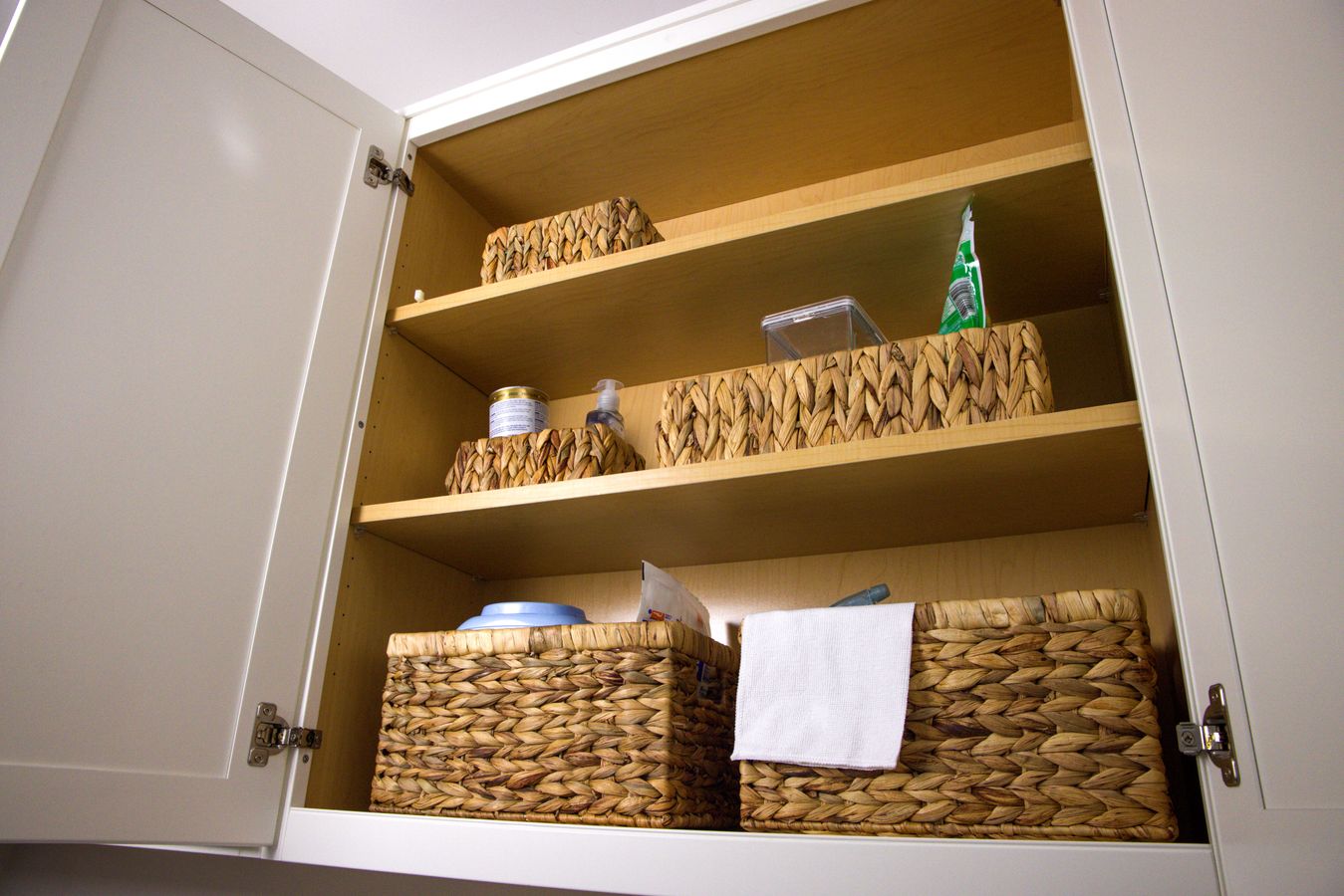Kitchen cabinet organized with wicker baskets that can be pulled forward for easier access