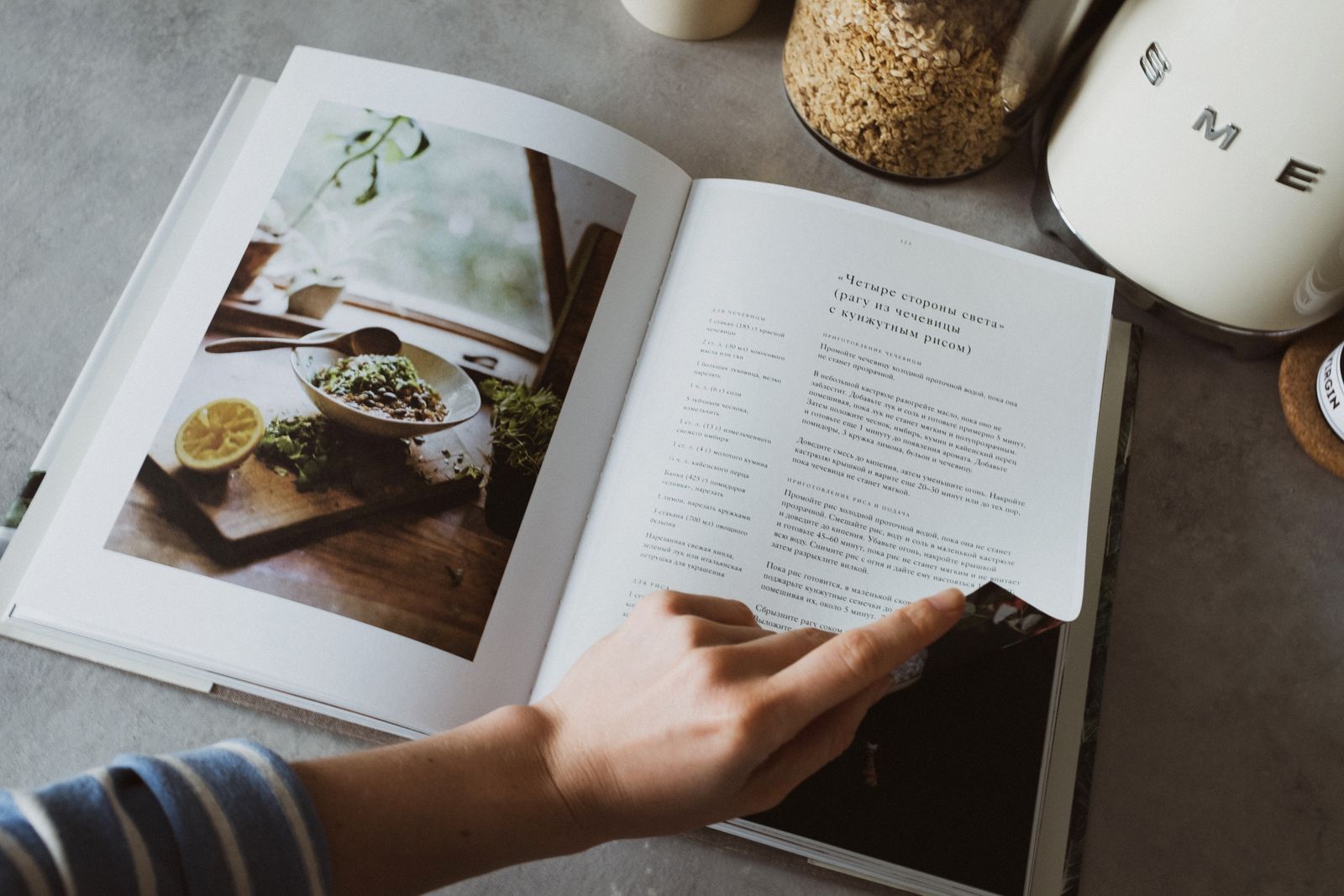 A hand pointing to a recipe in an open cookbook
