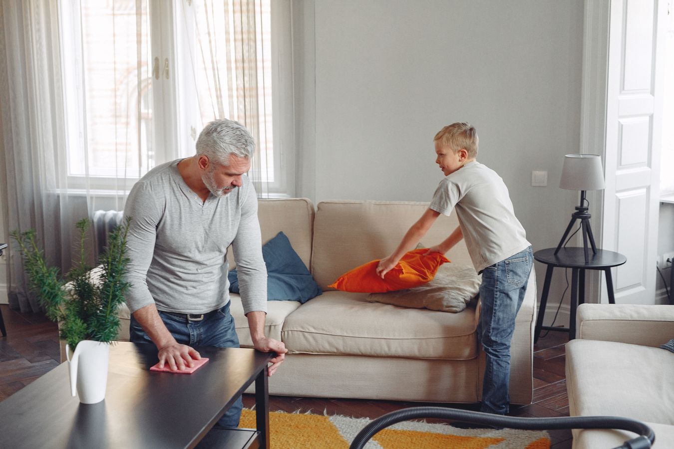 Father and son cleaning and tidying a living room surface together