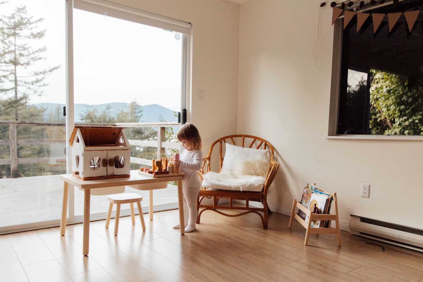 A child using a small play table beside the living-room window