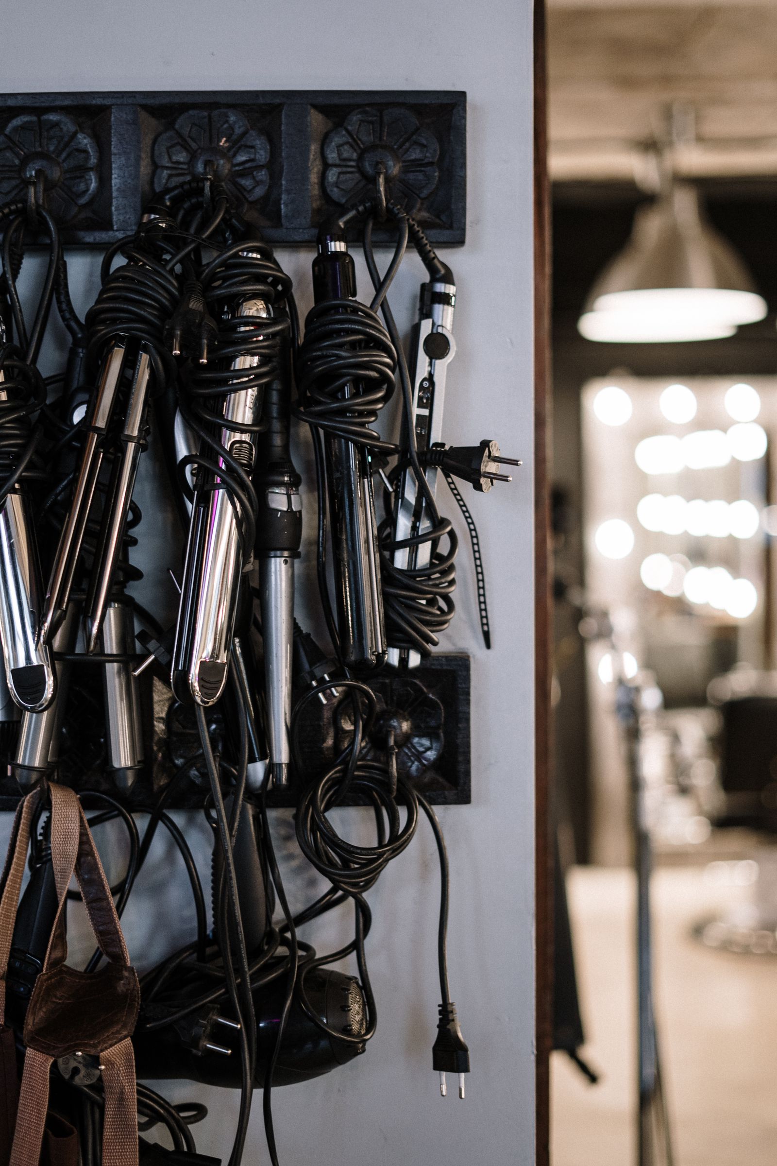 Several corded hair tools hanging at a salon station