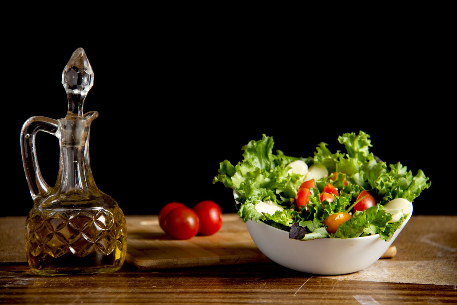 A small bowl of mixed salad beside a glass oil cruet