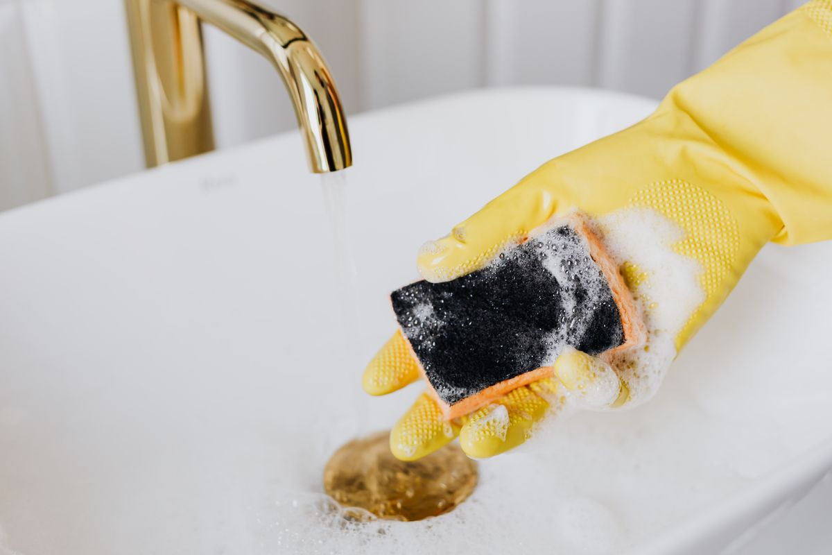 Gloved hand wiping a bathroom sink