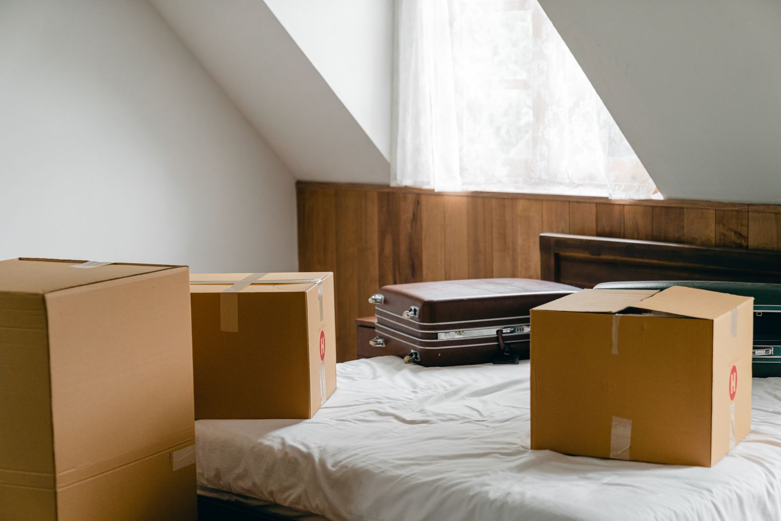 Cardboard boxes and suitcases temporarily grouped on a bed
