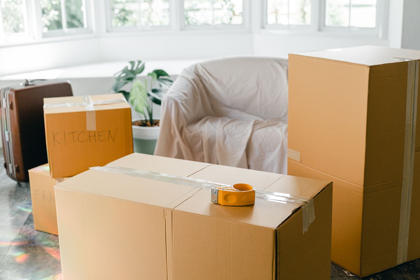 Cardboard moving boxes labeled for rooms, illustrating destination-based packing before downsizing