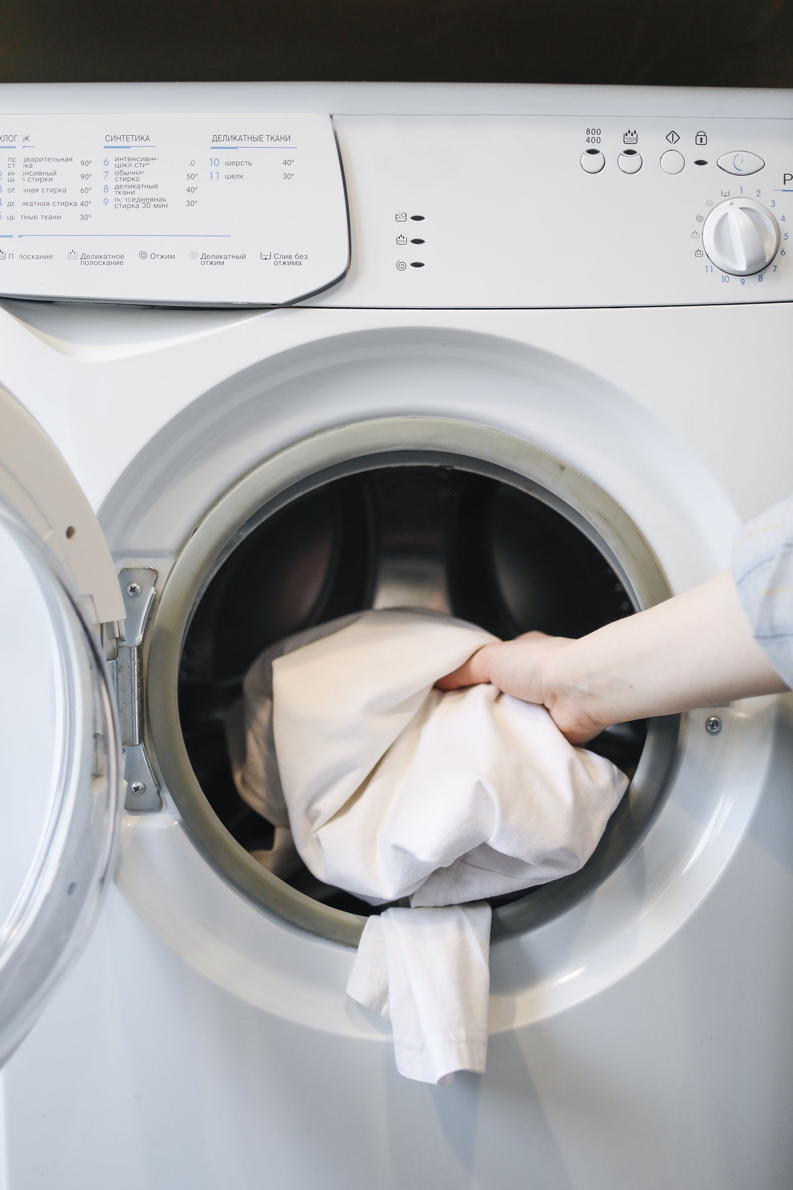 Close-up of laundry being placed through a front-load washer door