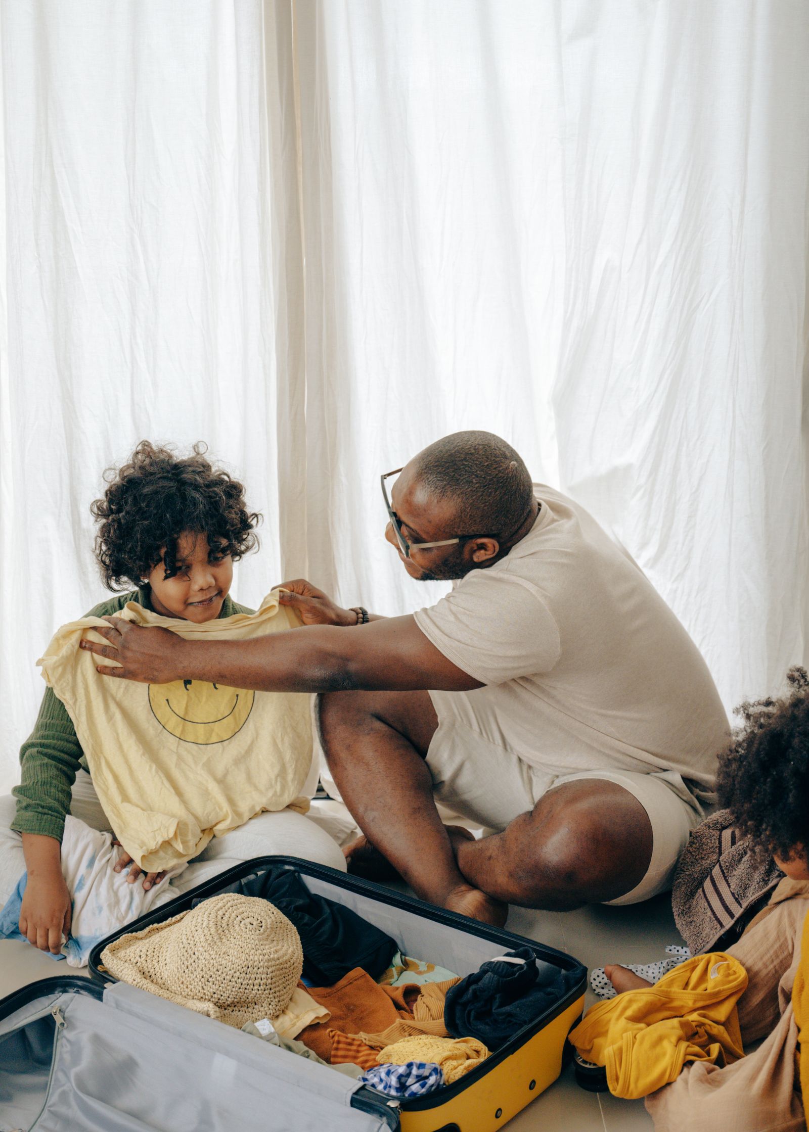 An adult helping a child beside an open suitcase