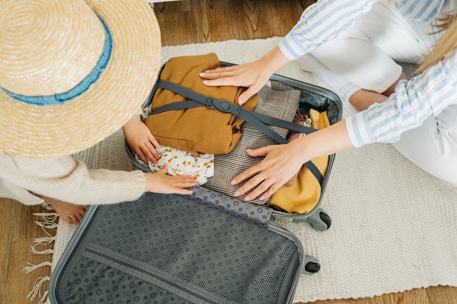 An adult and child arranging clothing in an open suitcase