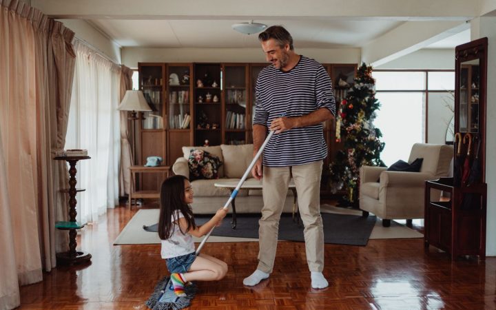 Father and daughter cleaning together in a living room during a family home reset