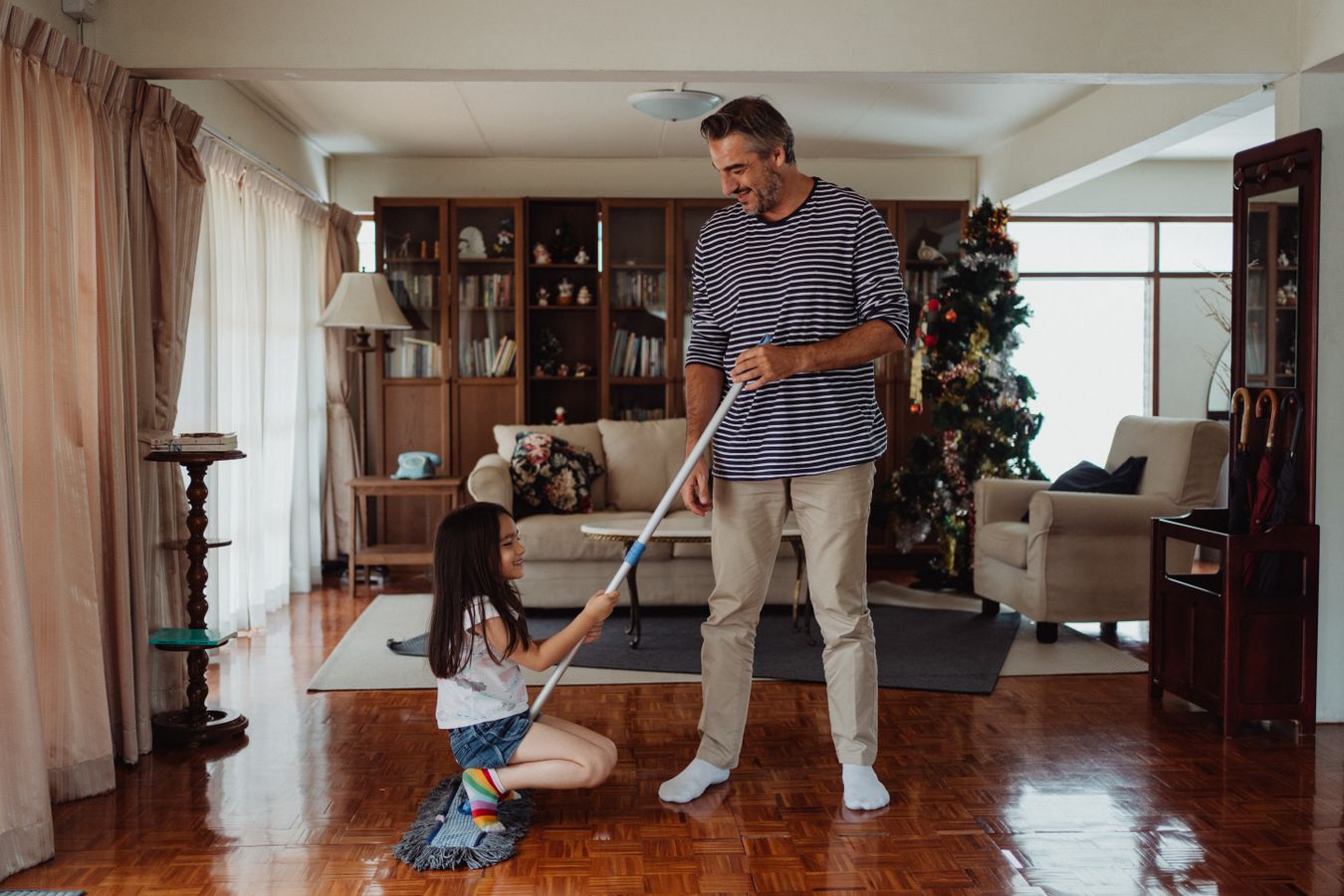 Father and daughter cleaning together in a living room during a family home reset