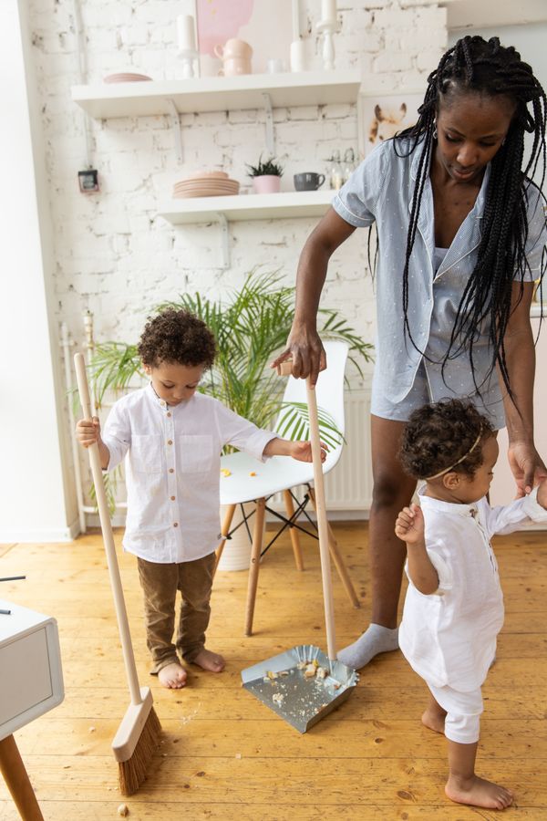 Mother and children sweeping a living room together as part of a household reset