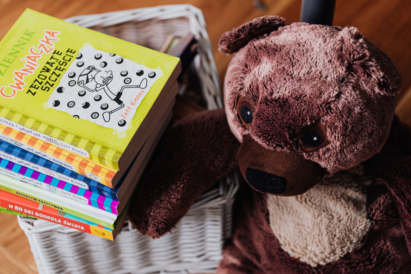 Children’s books beside a teddy bear in a basket