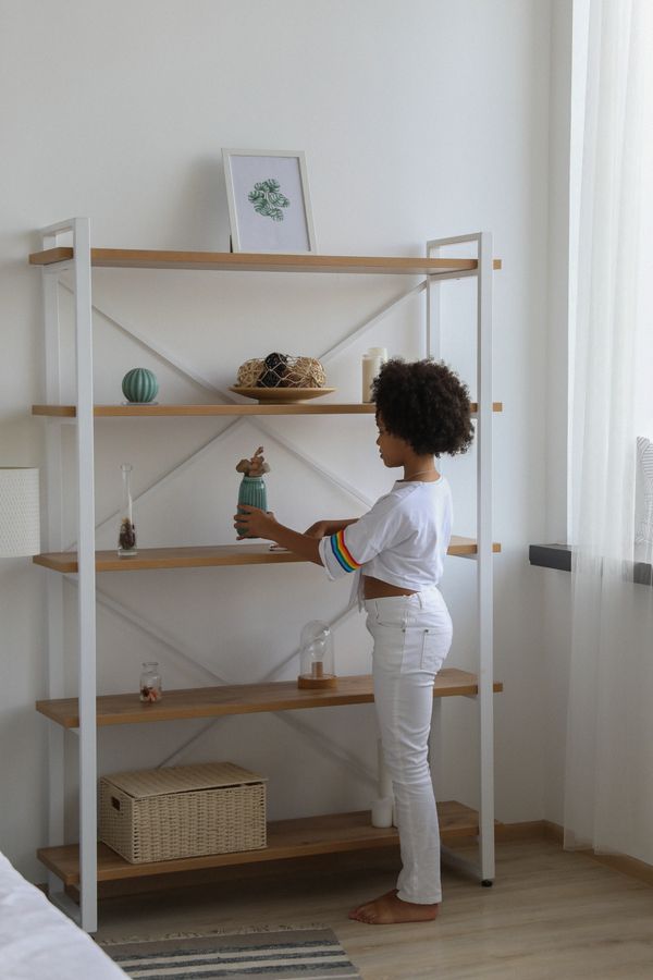 Young child cleaning and organizing a low wooden shelf at home