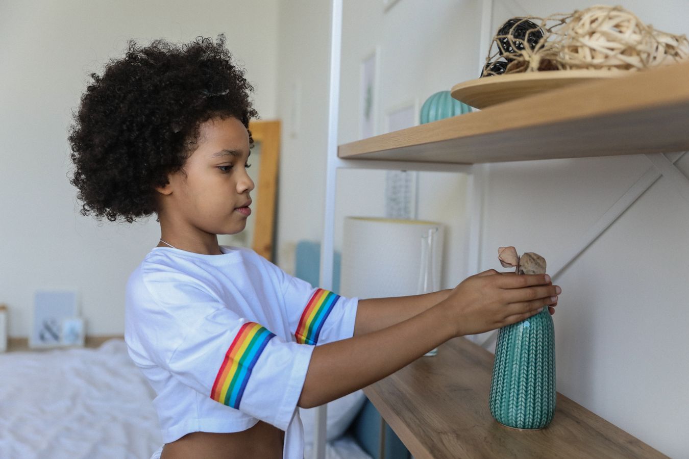 Child arranging items on a low bedroom shelf, illustrating reachable storage