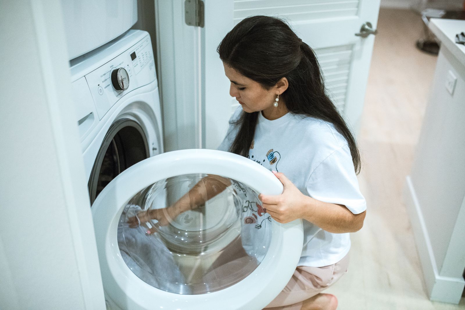 Person kneeling beside a front-load washing machine