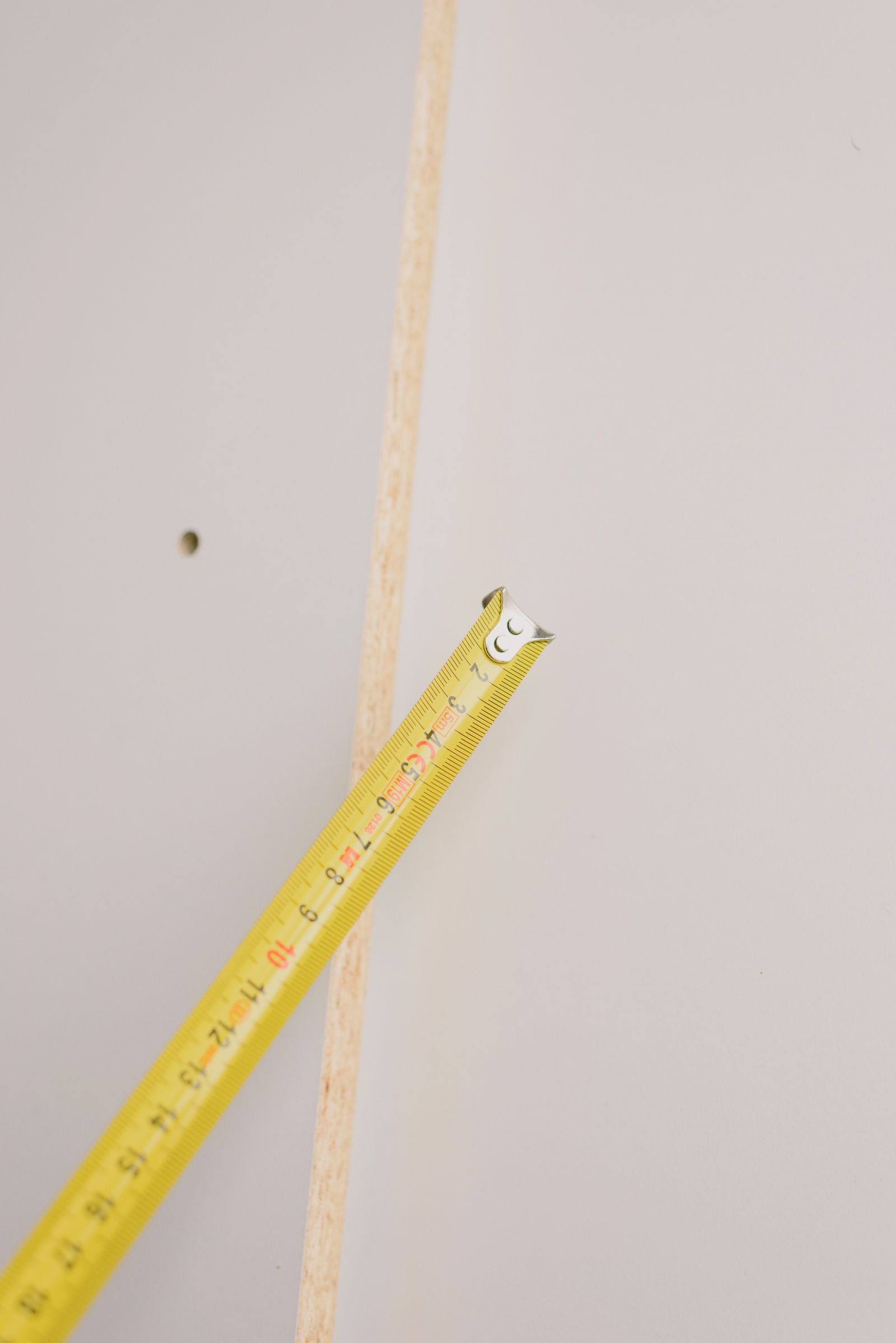 A tape measure extended diagonally beside a wall