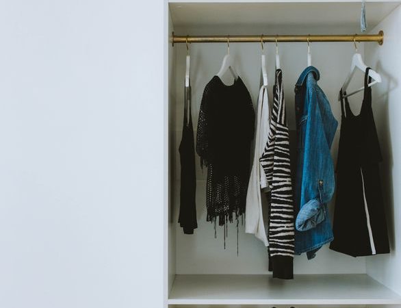 Neatly organized closet with clothes, shoes, and storage boxes divided into visible sections