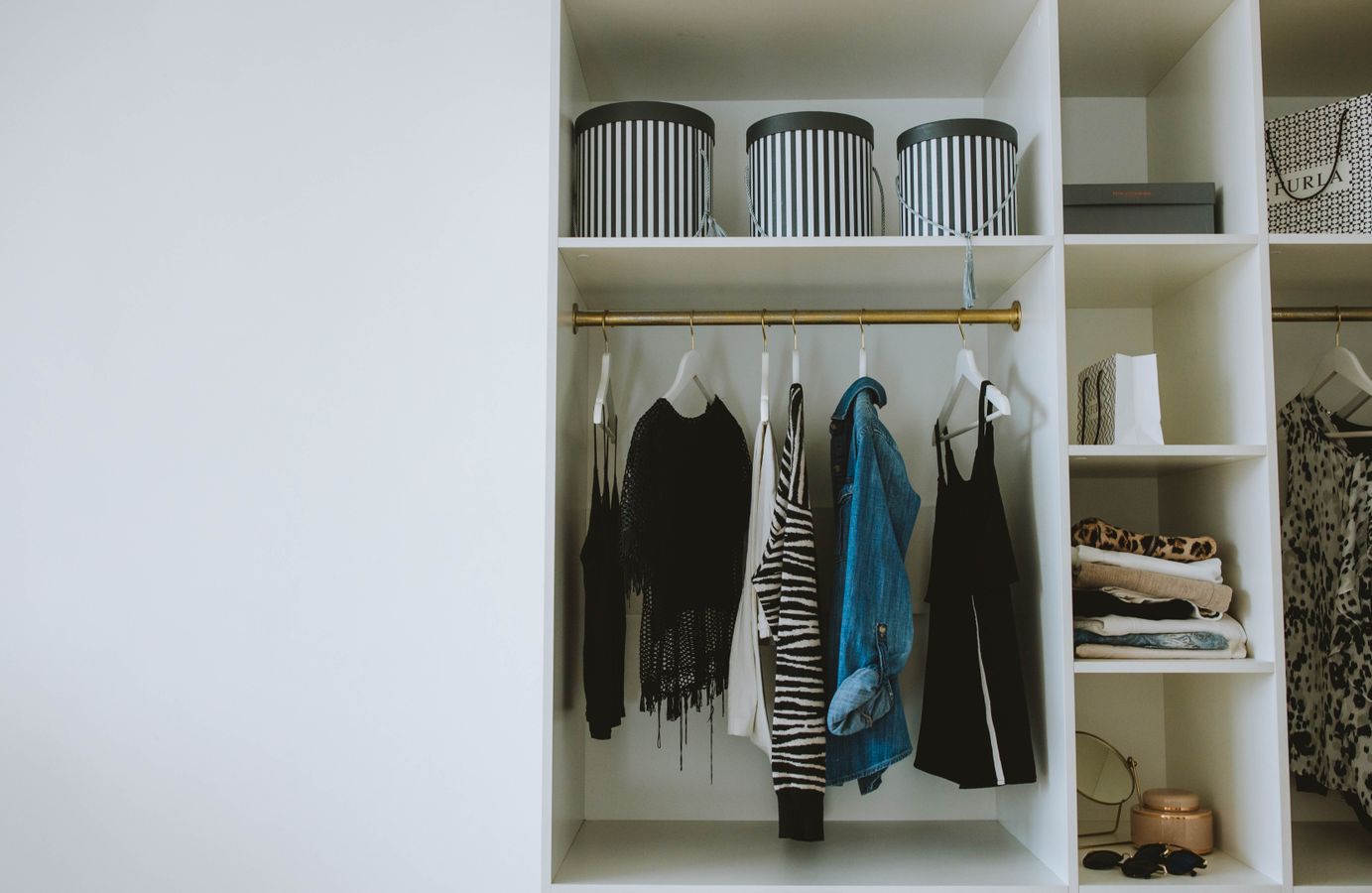 Organized wardrobe with hanging clothes, shelves, and storage boxes illustrating clear shared closet zones