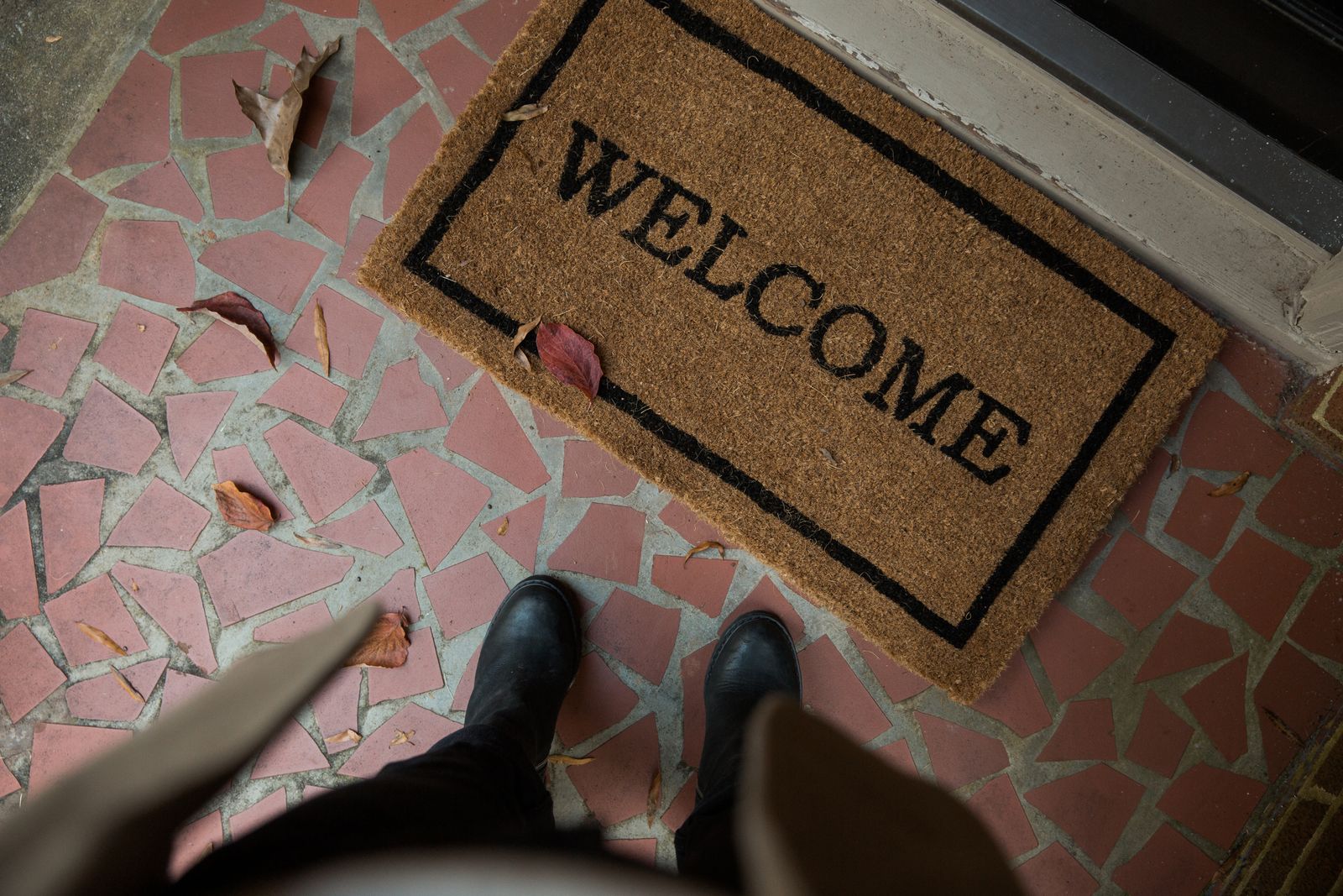 Boots standing beside a doormat at a home entrance