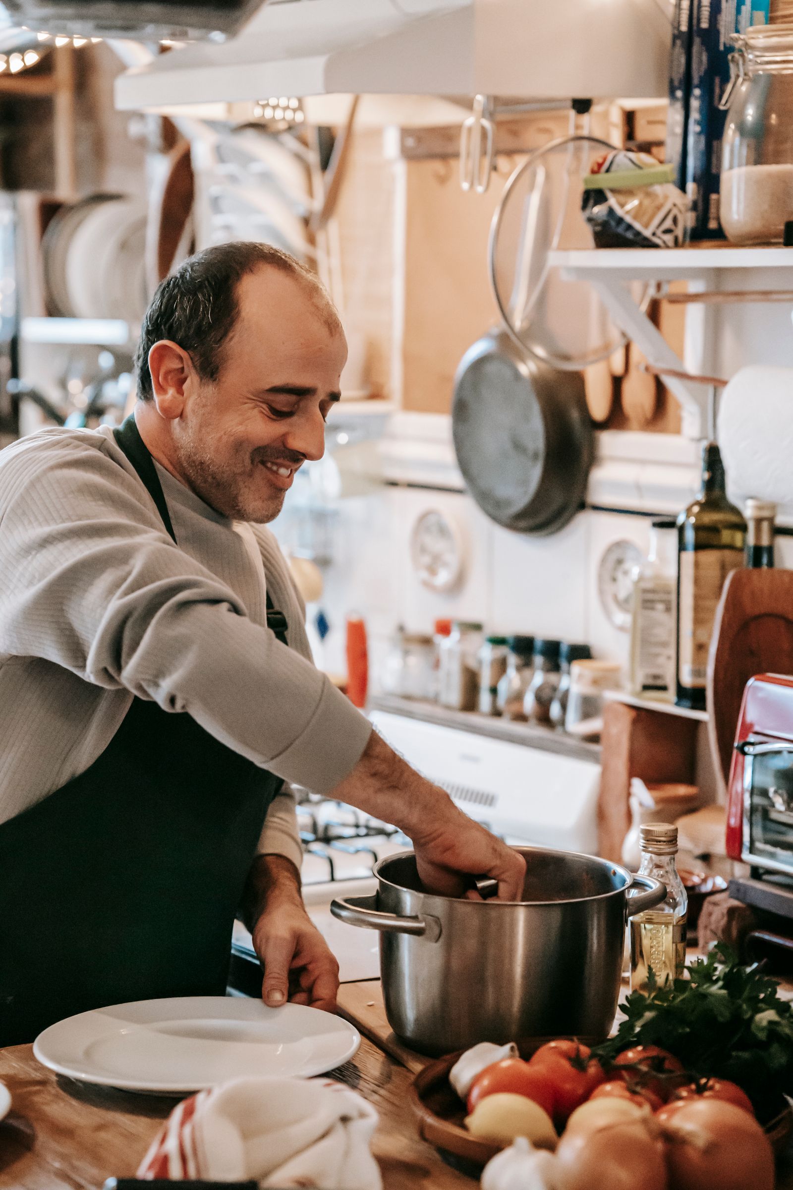 A cook preparing food in a saucepan in a kitchen