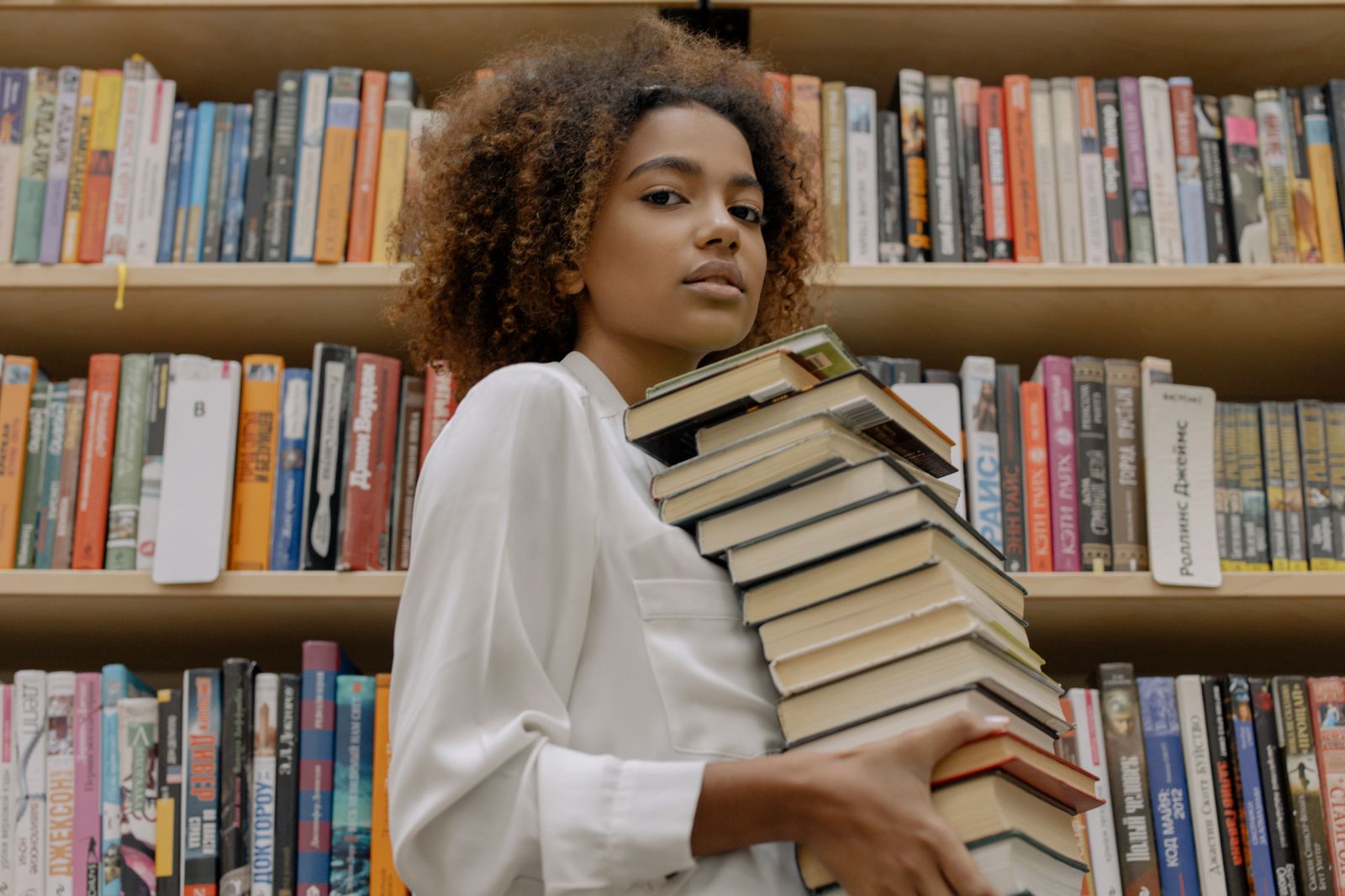 A woman carrying a stack of books in a library