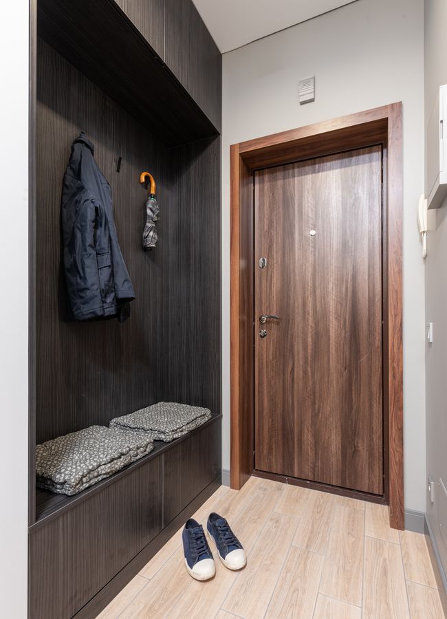Minimal hallway with coat hooks, shoes, and organized storage near the door