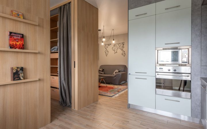 Modern small apartment with kitchen, shelving, and living area organized into functional zones