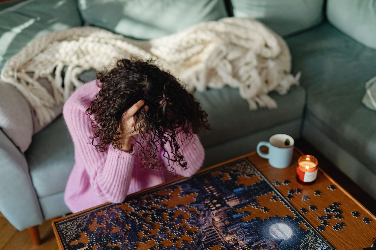 A person beside an unfinished puzzle on a low table