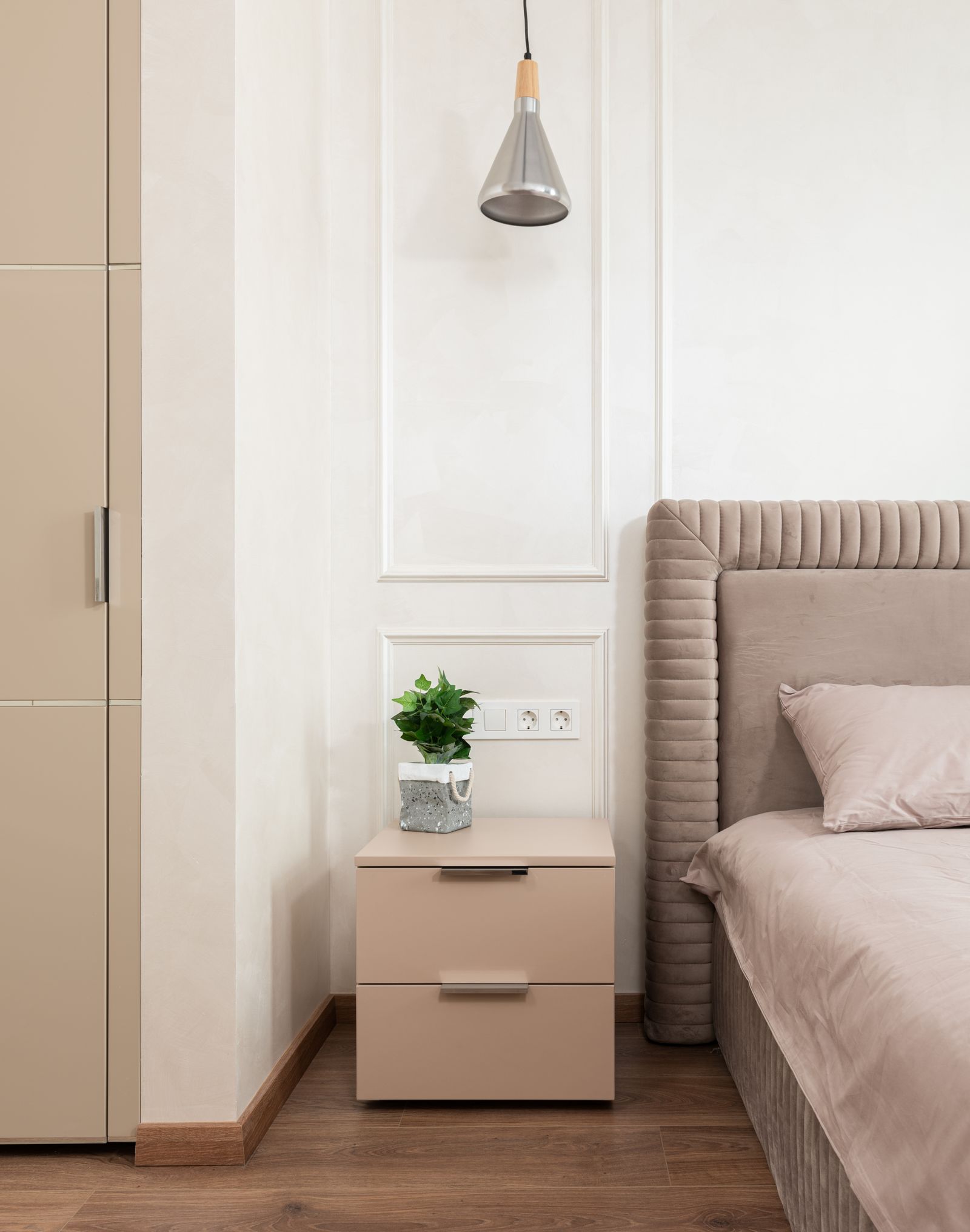 A bedroom bedside table with a plant and clear surrounding floor