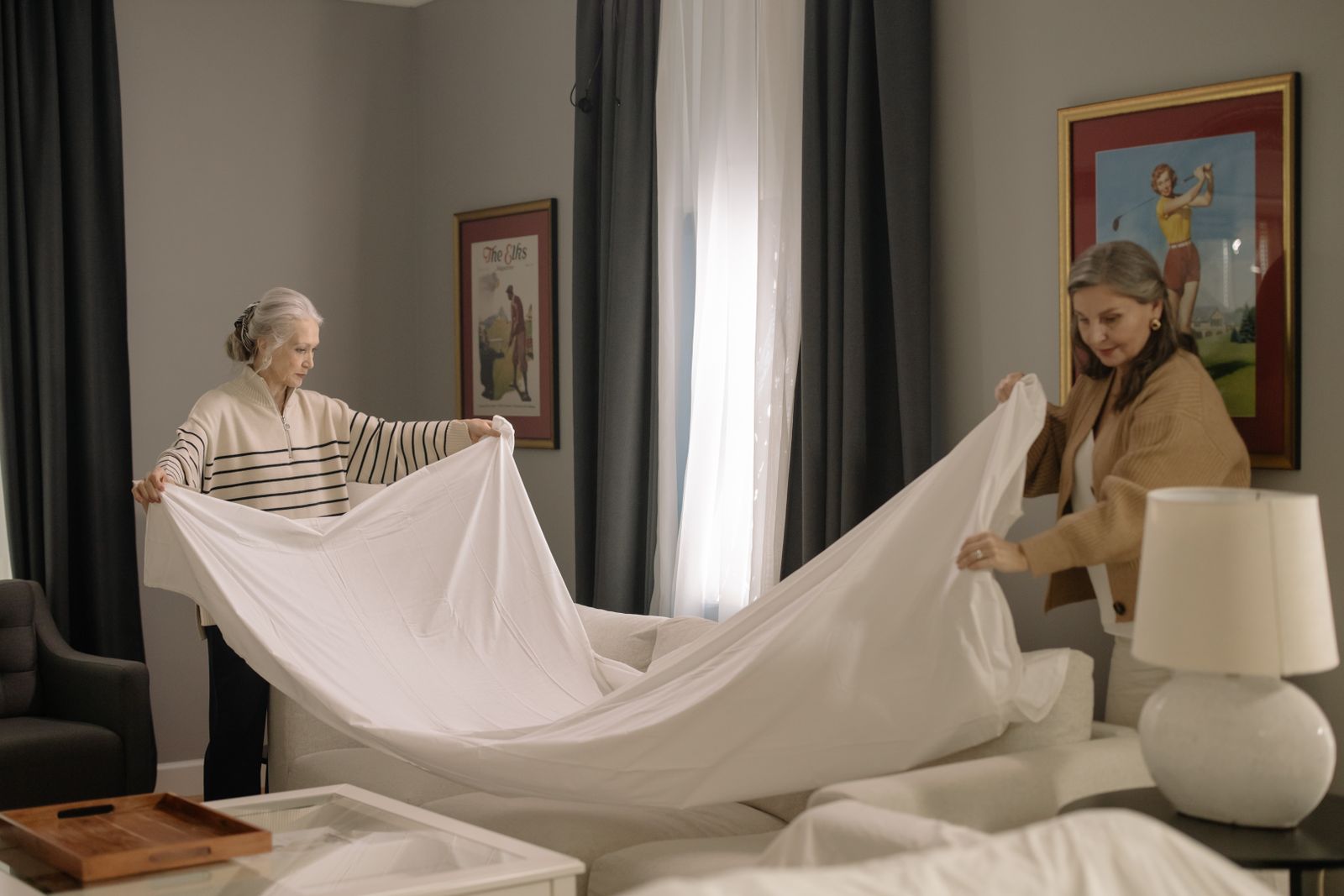 Two people arranging a blanket over a sofa