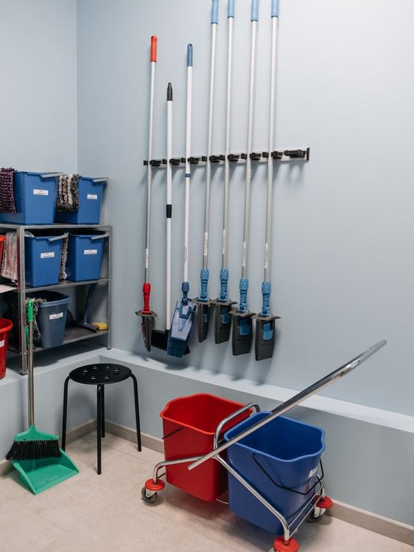 Organized mops, buckets, and cleaning tools stored together in a utility area