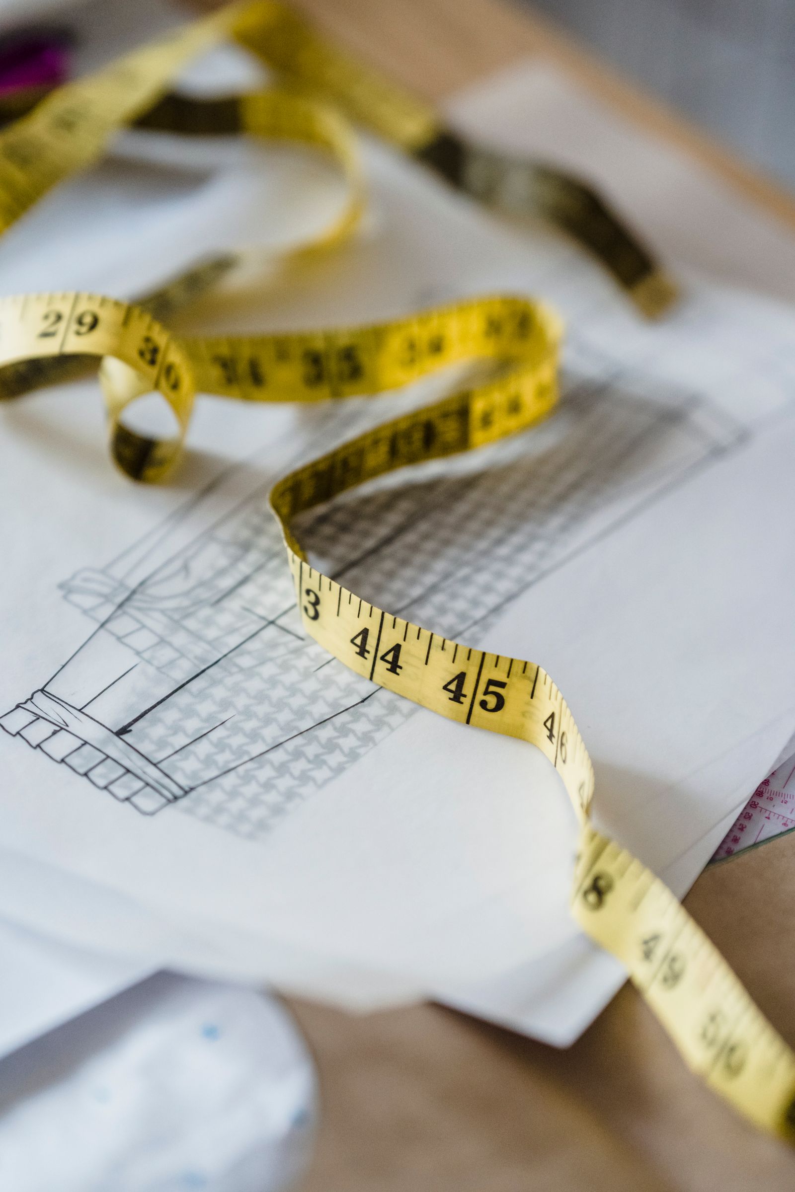 A flexible measuring tape lying on a sketched plan