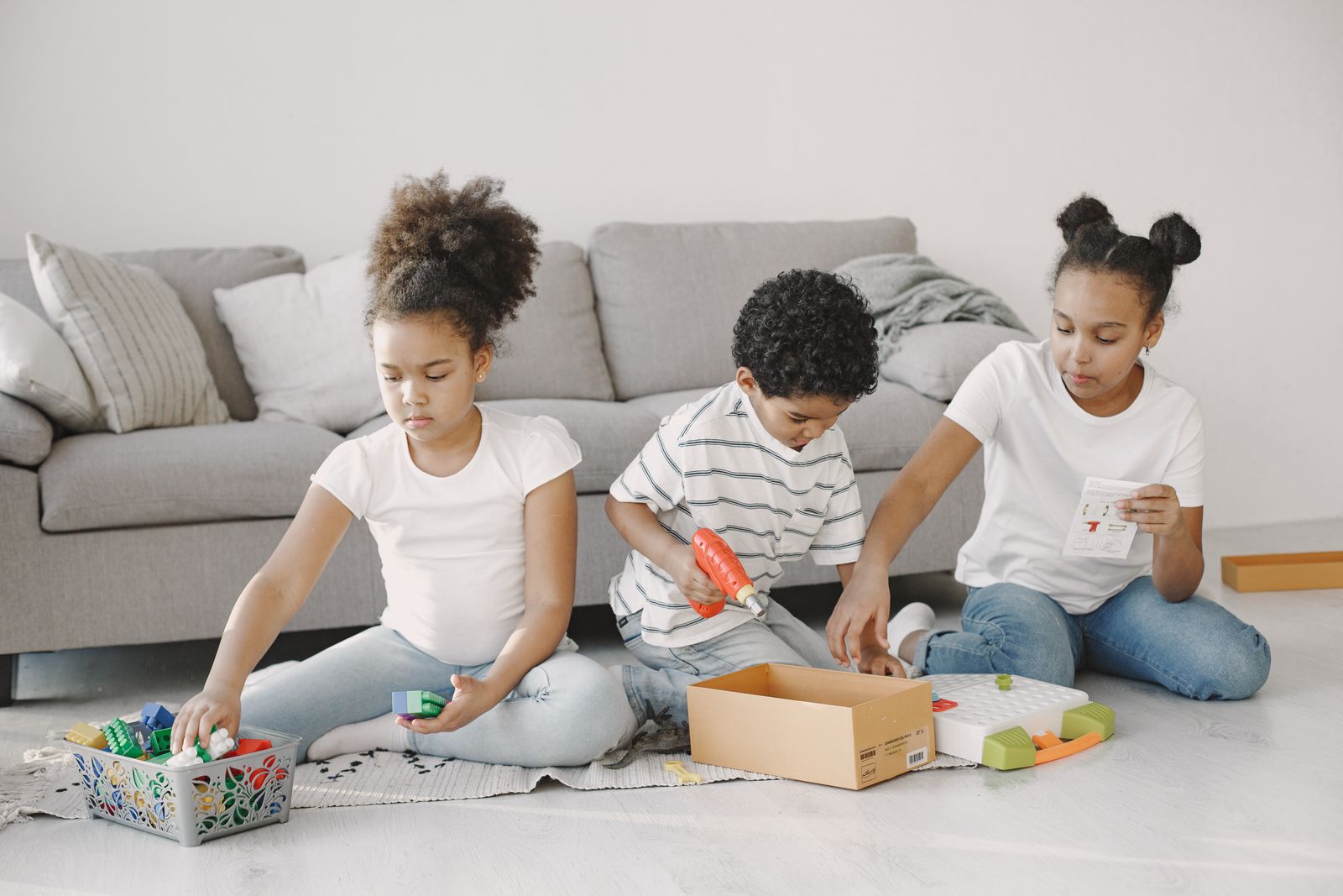 Three children playing with building toys on a living-room rug