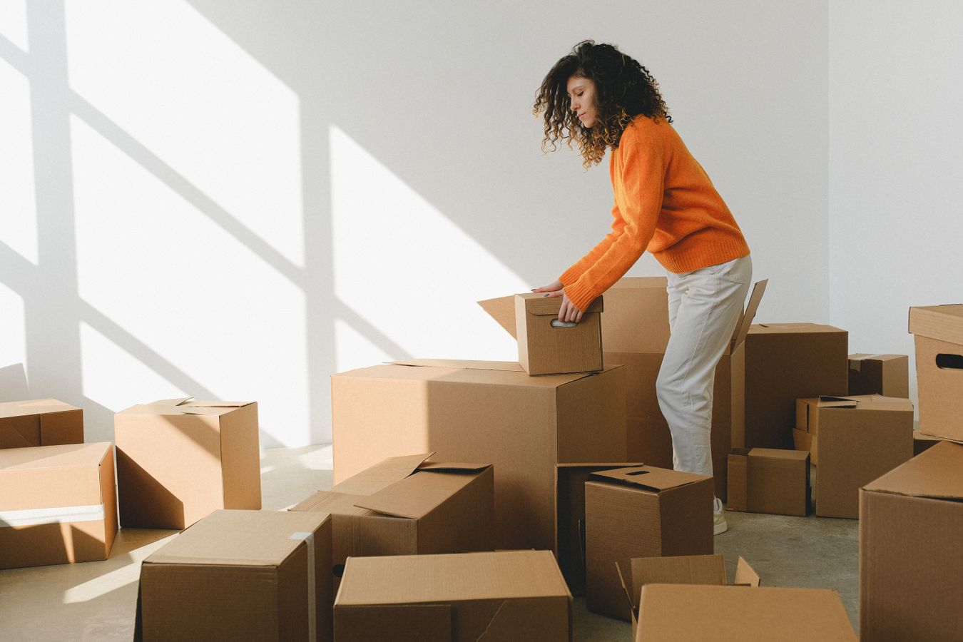 Woman sorting and arranging cardboard boxes while preparing for a move