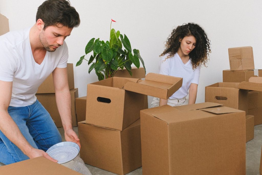 Couple packing household belongings into cardboard boxes before moving to a new home