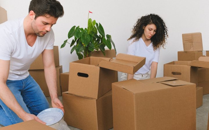 Couple packing household belongings into cardboard boxes before moving to a new home