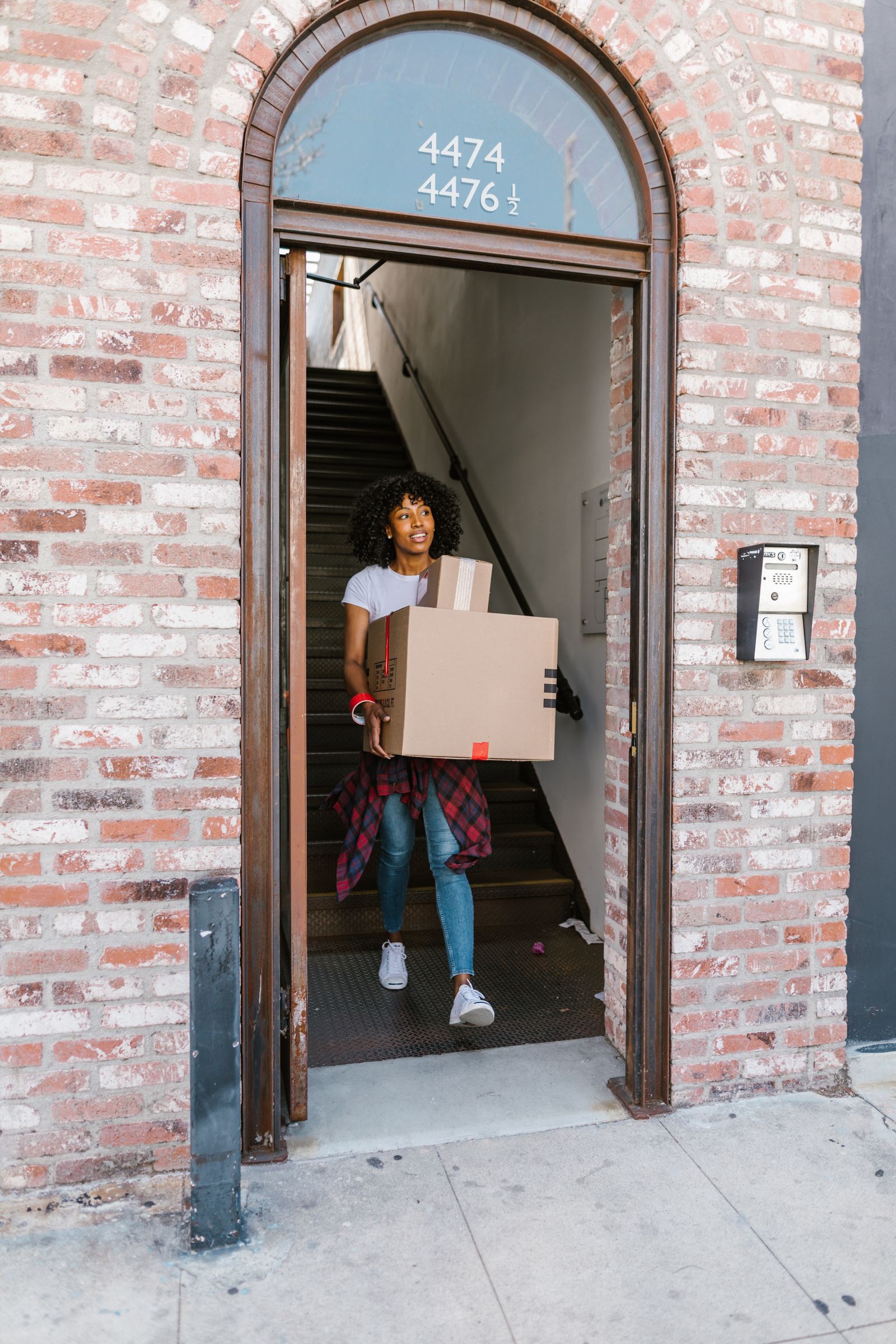 A person with a moving box at a building entrance