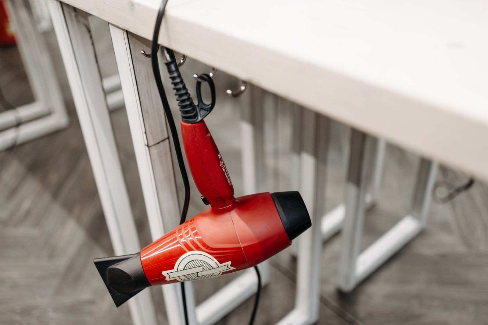 A red hairdryer hanging from a holder beside a work surface