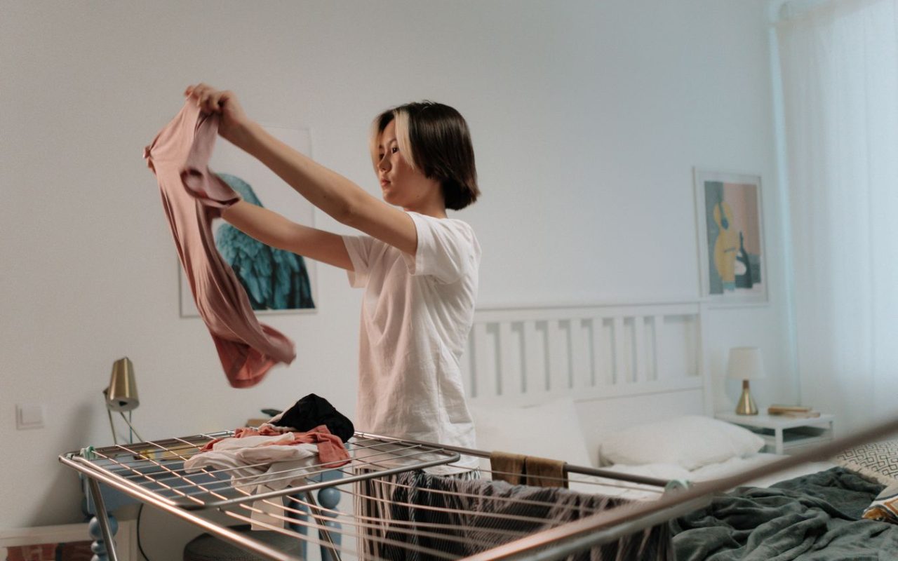 Woman folding clothes in a tidy bedroom as part of a simple put-away routine