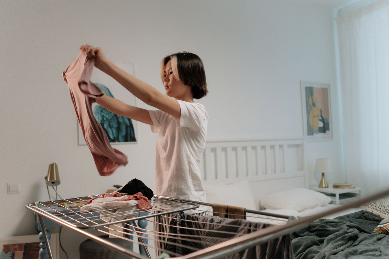 Woman folding clothes in a tidy bedroom as part of a simple put-away routine