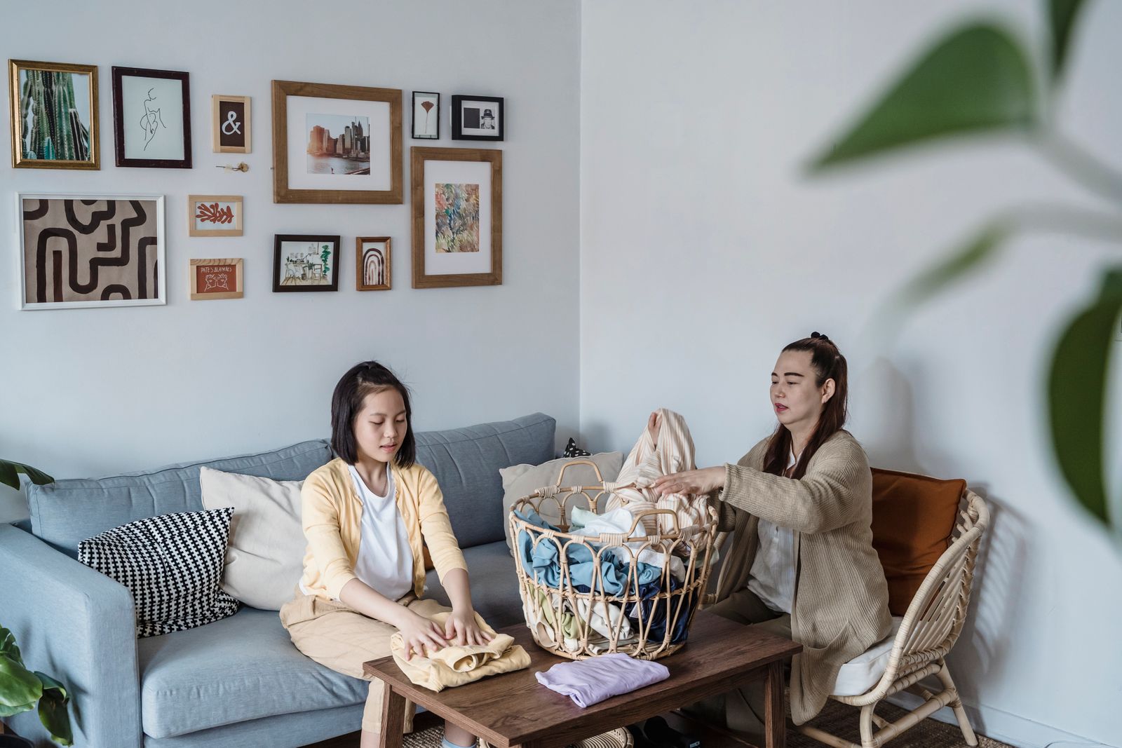 Mother and daughter folding laundry together on a sofa
