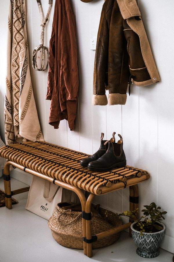 Entryway with hanging coats, shoes, woven storage, and a bench