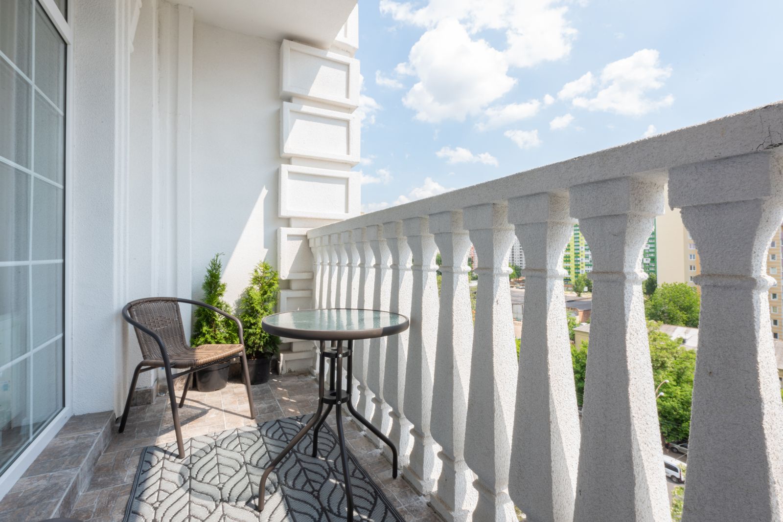 Two metal chairs and a round table beside a balcony railing