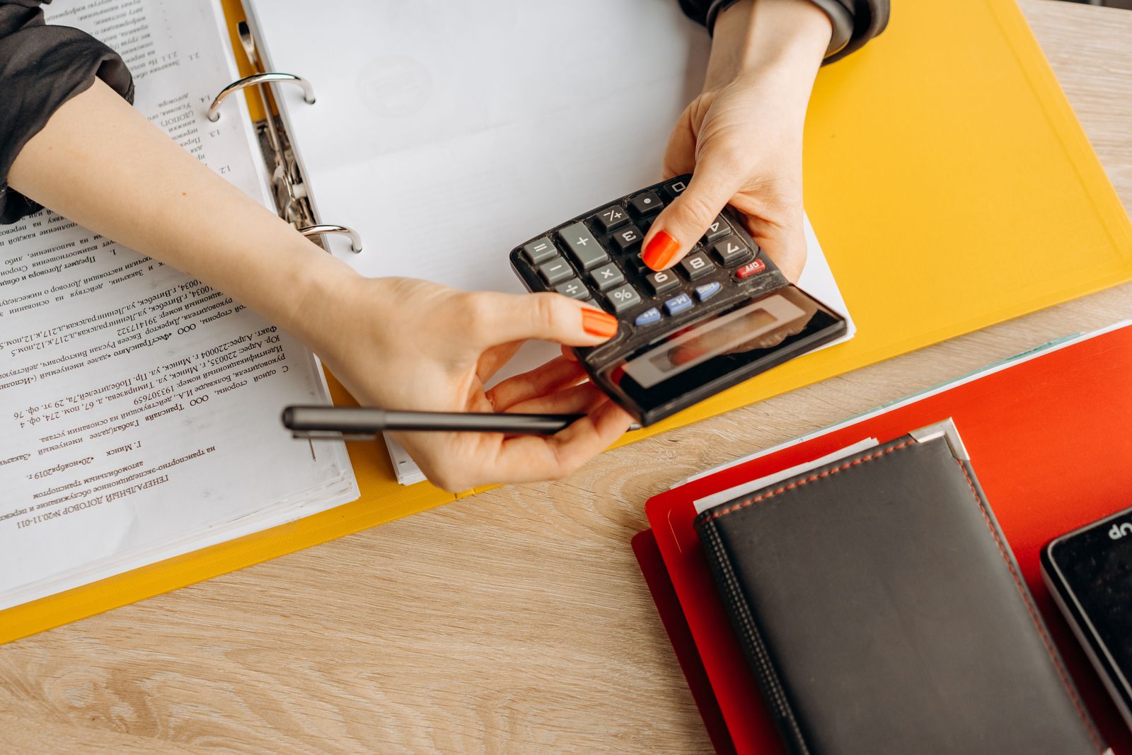 Hands reviewing documents with a calculator and folders