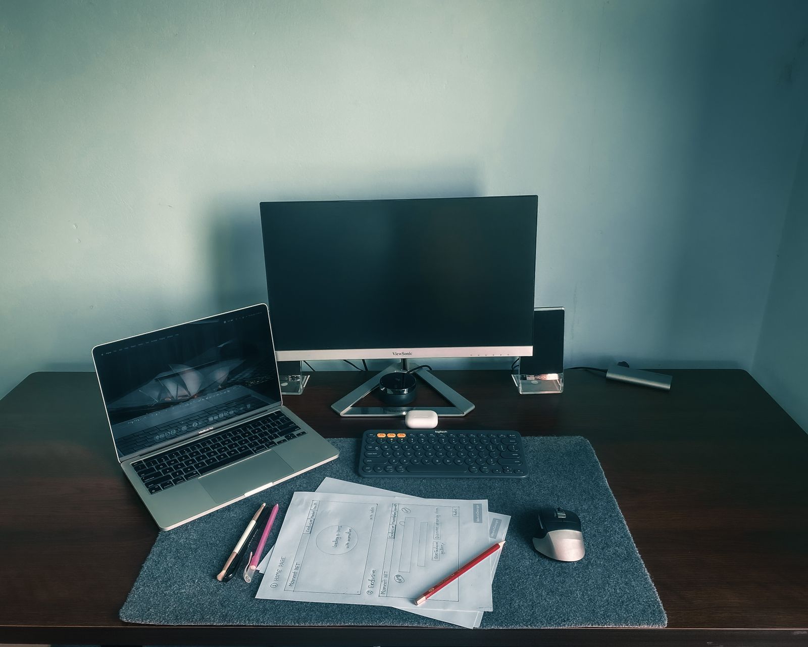 A monitor and laptop sharing a desk with loose reference sheets