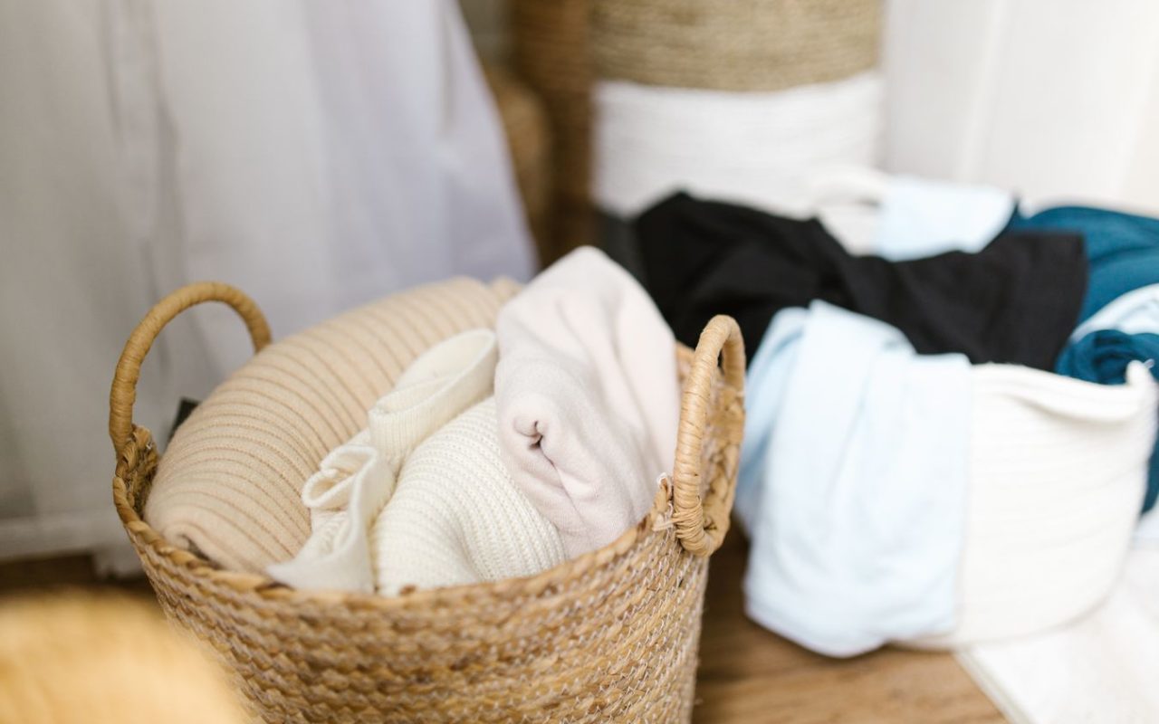 Children’s clothing organized in woven baskets in a small bedroom storage area
