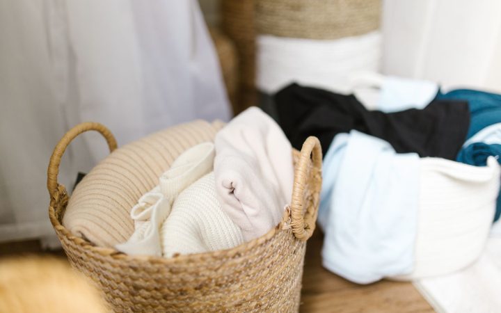 Children’s clothing organized in woven baskets in a small bedroom storage area
